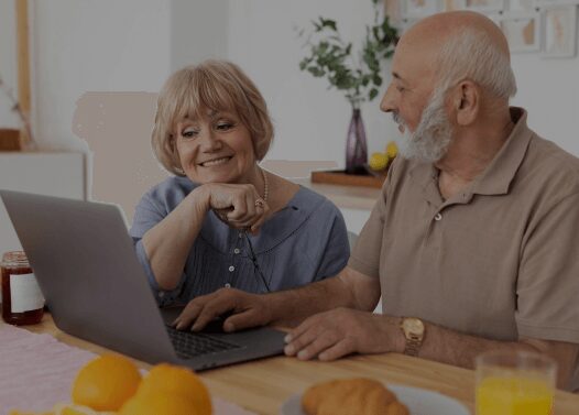 Elderly couple using a laptop together happily.
